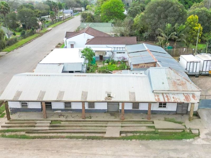 Aerial view of a commercial property featuring a long structure with corrugated metal roofing, brick pillars, and concrete steps.