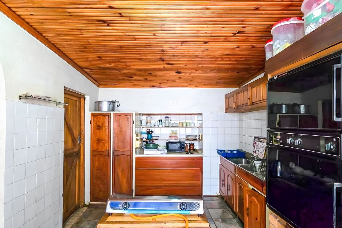 A dated kitchen featuring wooden cabinetry, a tongue and groove timber ceiling, built-in oven, and tiled splashbacks, offering potential for a modern renovation.