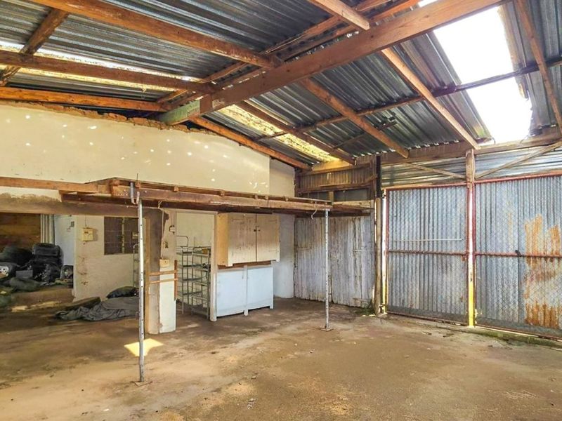 A large, open-plan utility or workshop space featuring exposed timber rafters, corrugated metal roofing, and concrete flooring, suitable for industrial or storage use.