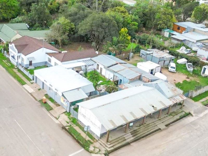 Aerial view of a commercial property complex featuring multiple structures with corrugated metal roofing and a covered veranda area.