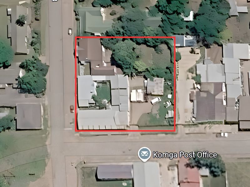 An aerial view of the commercial property site, highlighting the building layout, roof structures, and surrounding grounds within the marked boundary.
