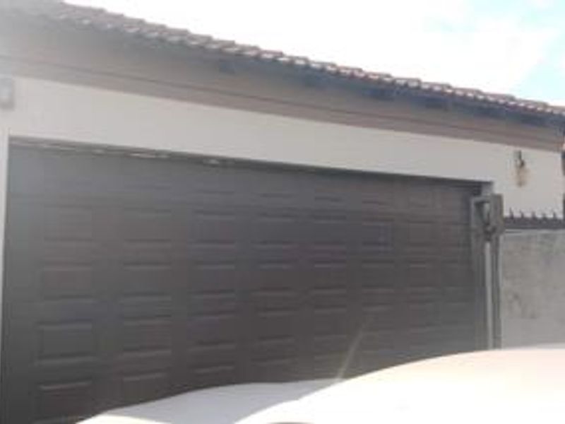Exterior view of a residential garage featuring a dark sectional door and tiled roof.