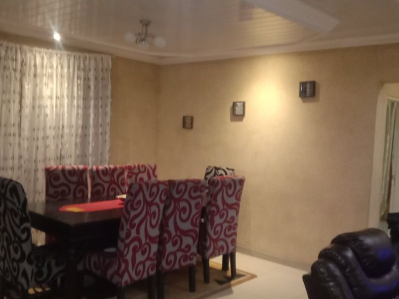 A dining room featuring tiled flooring, ceiling molding, and recessed lighting, providing a functional space for family meals.