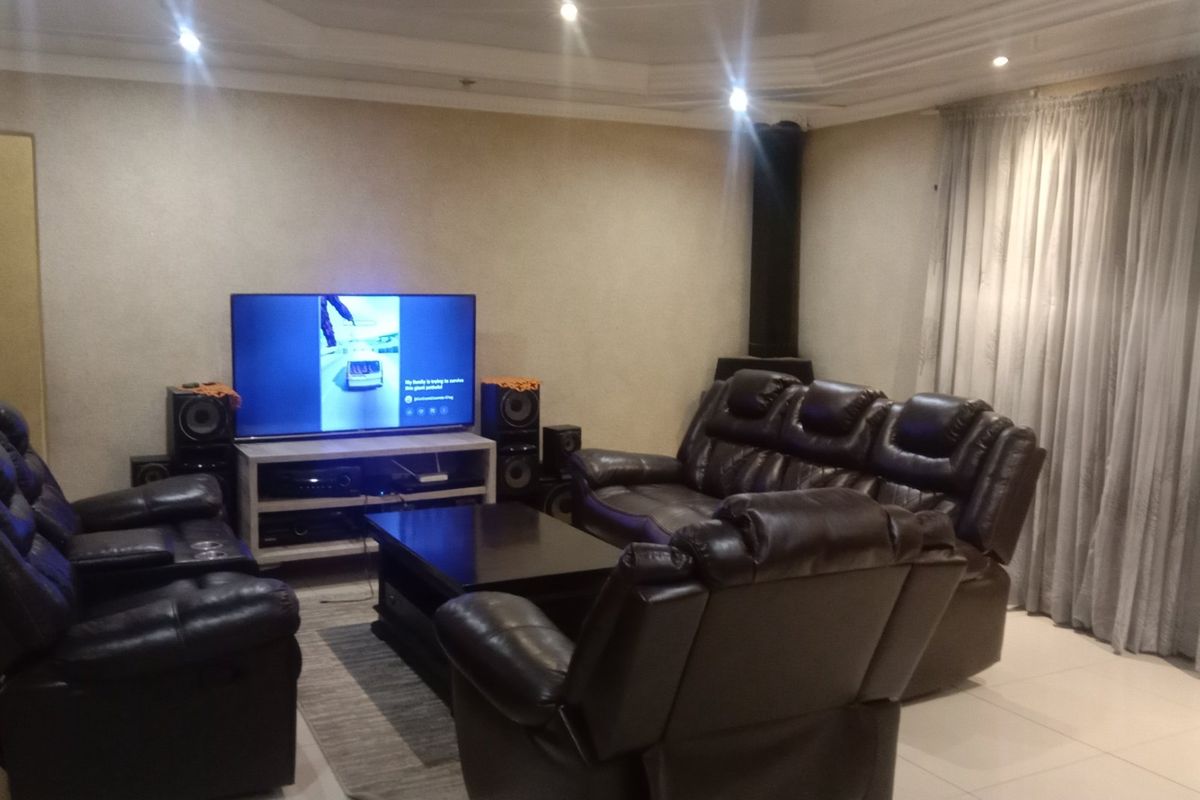 A comfortable living room featuring tiled flooring, a coved ceiling with recessed lighting, and a built-in fireplace.