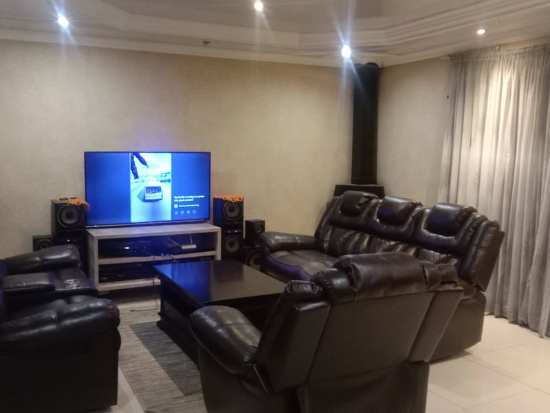 A comfortable living room featuring tiled flooring, a coved ceiling with recessed lighting, and a built-in fireplace.