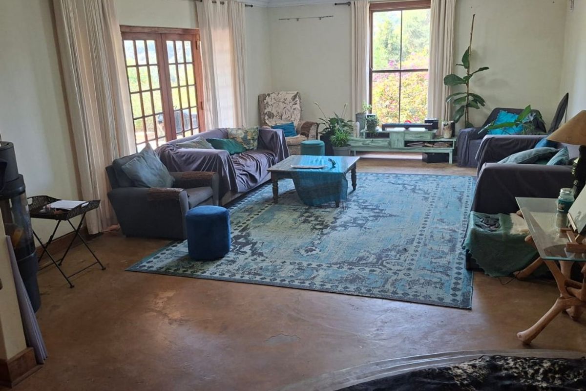 Spacious living room featuring polished concrete floors, large sash windows, and double french doors providing natural light and garden access.