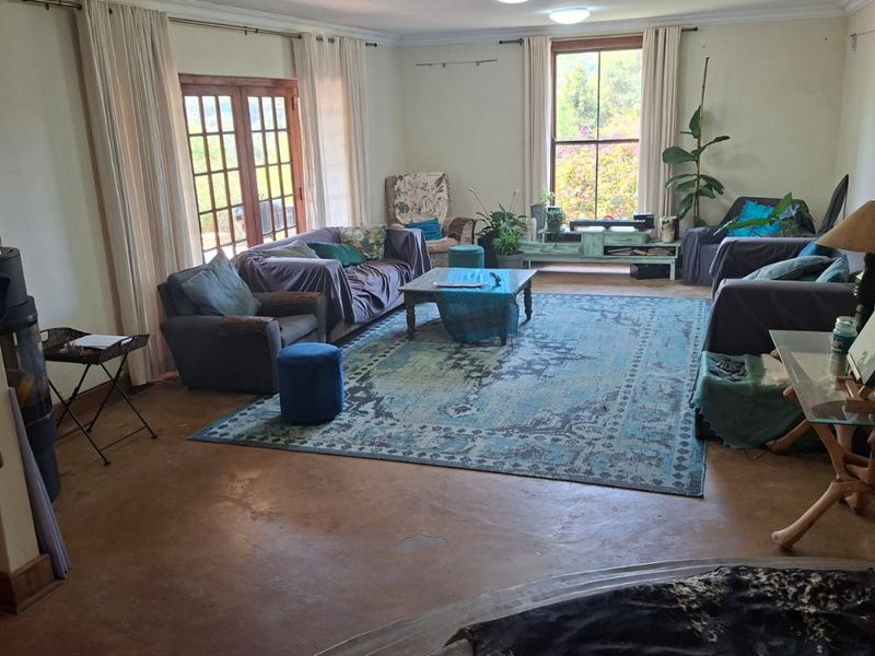 Spacious living room featuring polished concrete floors, large sash windows, and double french doors providing natural light and garden access.