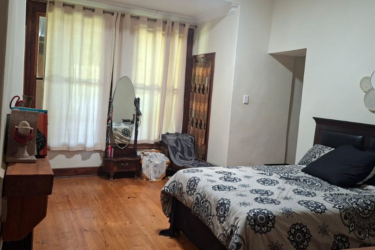 Spacious bedroom featuring original hardwood flooring, a fireplace, and large sash windows that provide ample natural light.