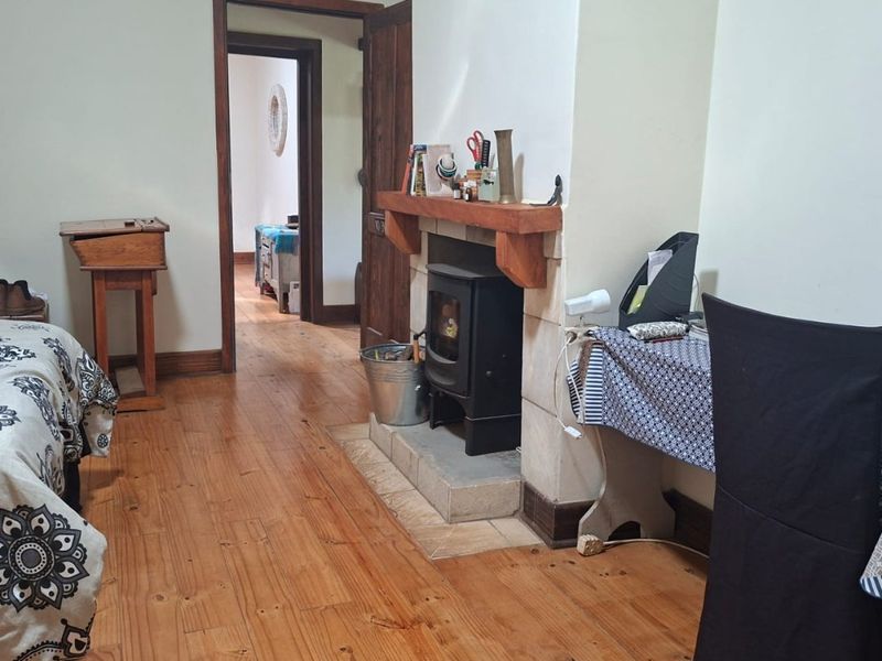 Bedroom featuring original wood flooring and a built-in fireplace with a timber mantel, providing a cozy and traditional atmosphere.