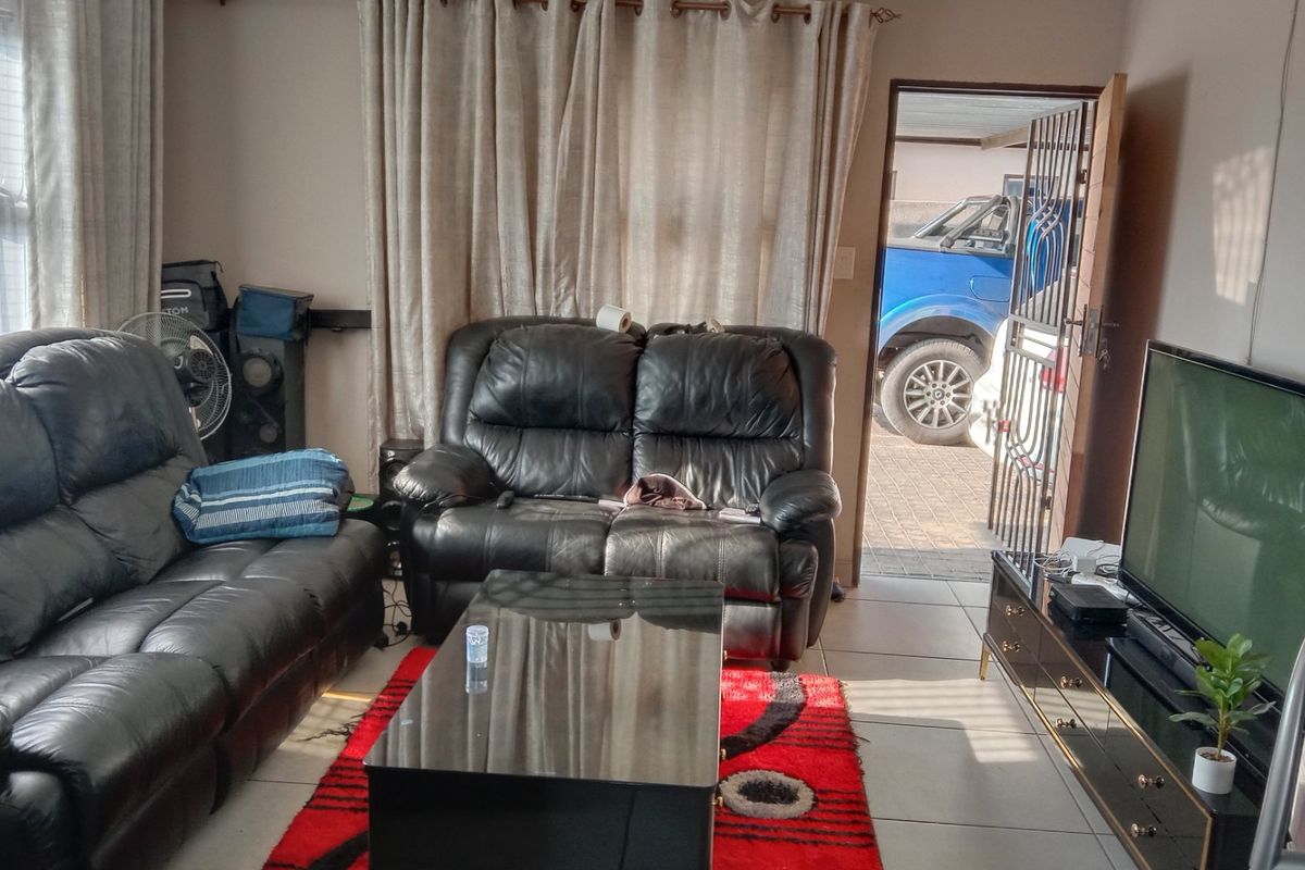 A living room featuring tiled flooring and direct access to the exterior via a security gate.