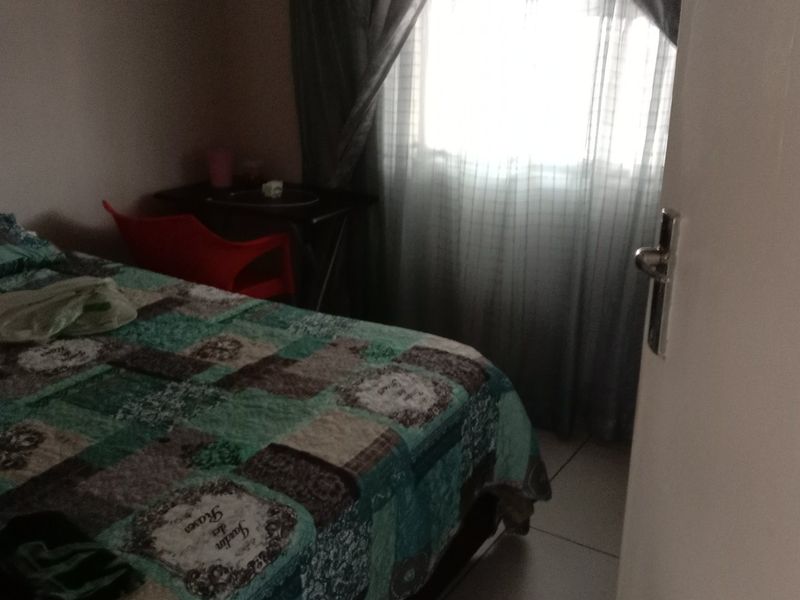 A standard bedroom featuring tiled flooring and window treatments, viewed from the doorway.