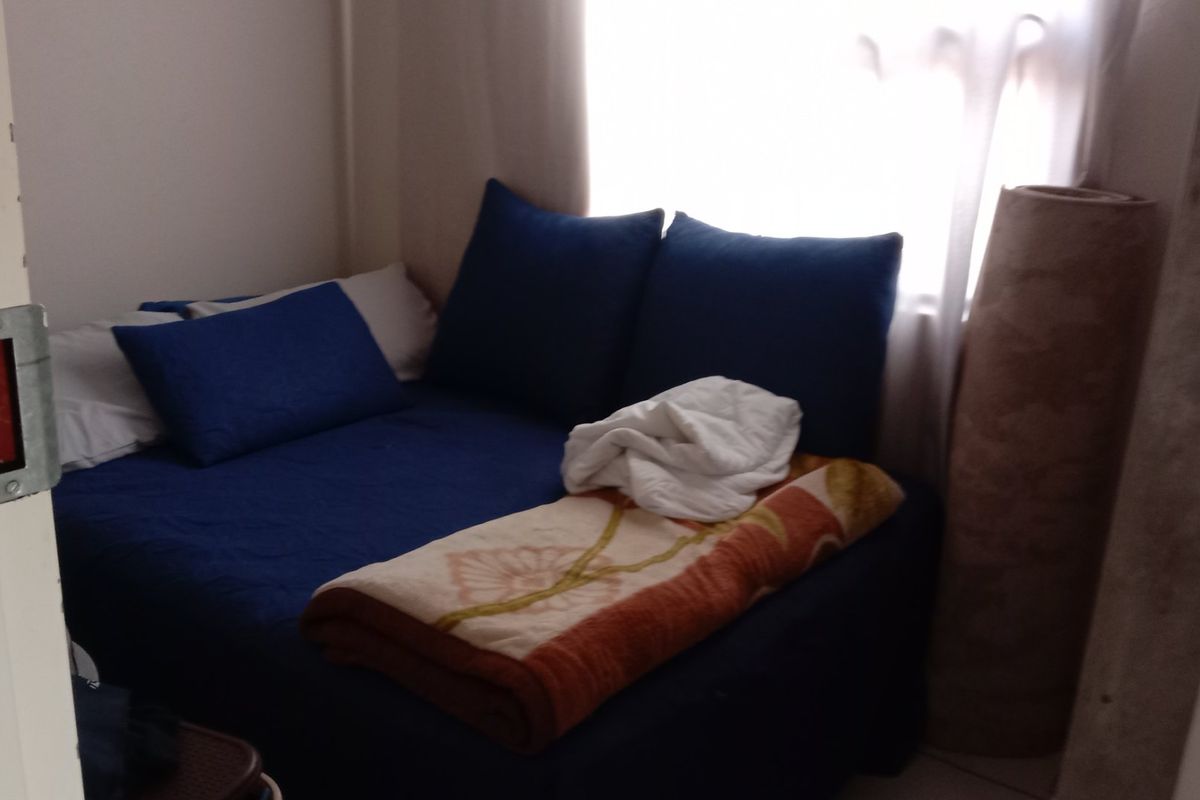 A compact bedroom space featuring a window and standard door frame, suitable for a single bed or study area.