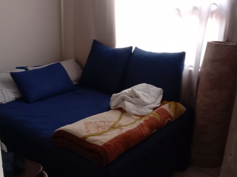 A compact bedroom space featuring a window and standard door frame, suitable for a single bed or study area.