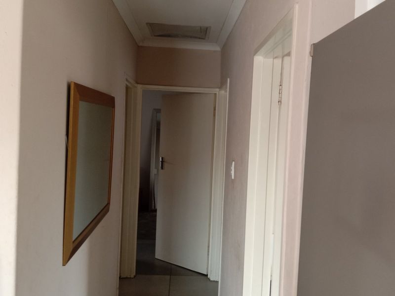 A functional interior hallway providing access to multiple rooms, featuring standard door frames and a ceiling access hatch.