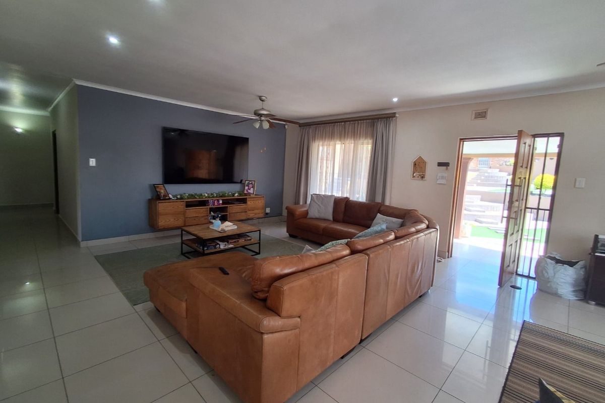 Spacious living room featuring tiled flooring, recessed lighting, a ceiling fan, and direct access to the exterior through a security gate.