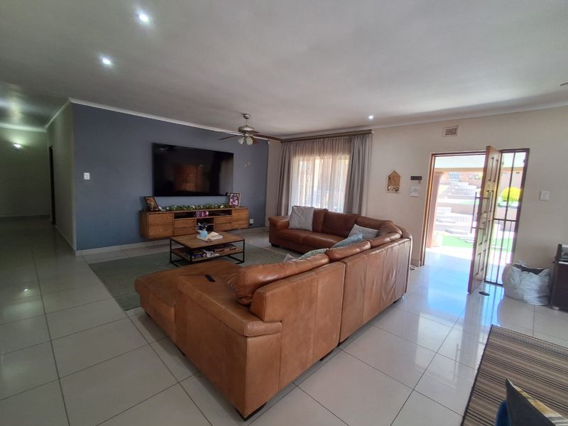 Spacious living room featuring tiled flooring, recessed lighting, a ceiling fan, and direct access to the exterior through a security gate.