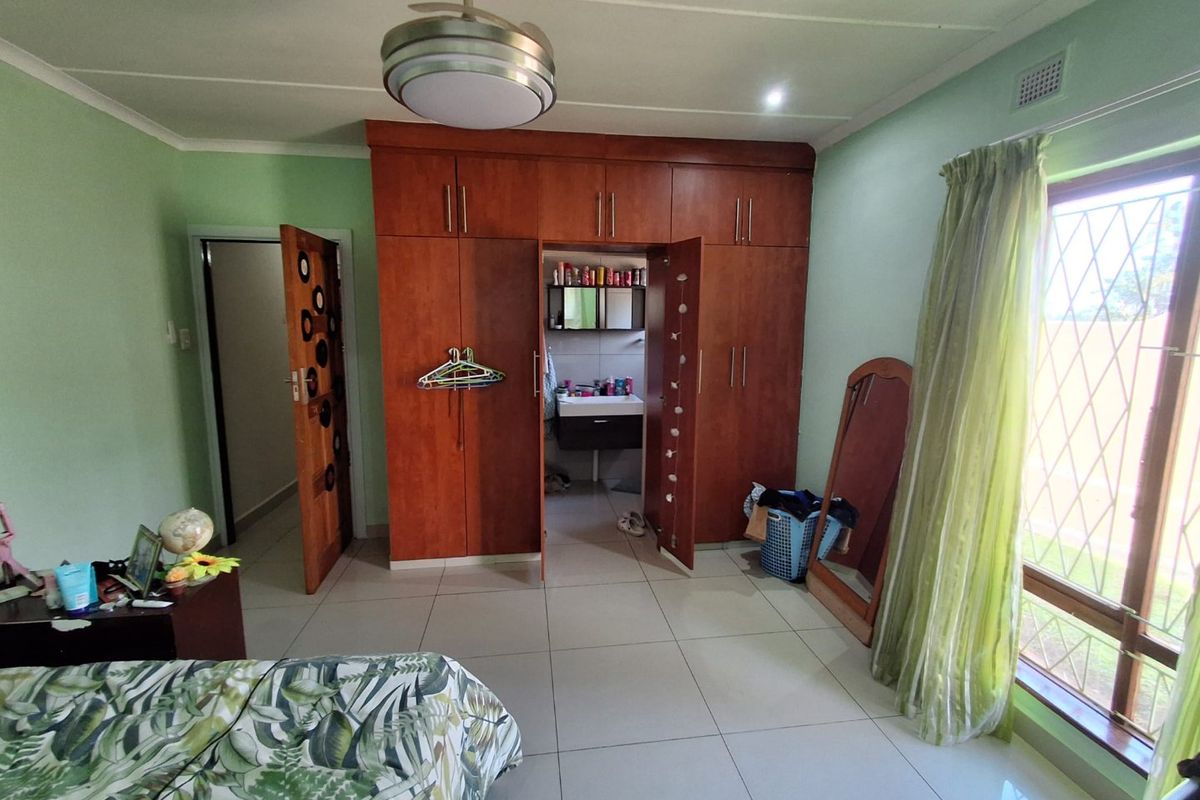 Bedroom featuring built-in wooden cupboards, tiled flooring, a ceiling fan, and an en-suite bathroom access point.