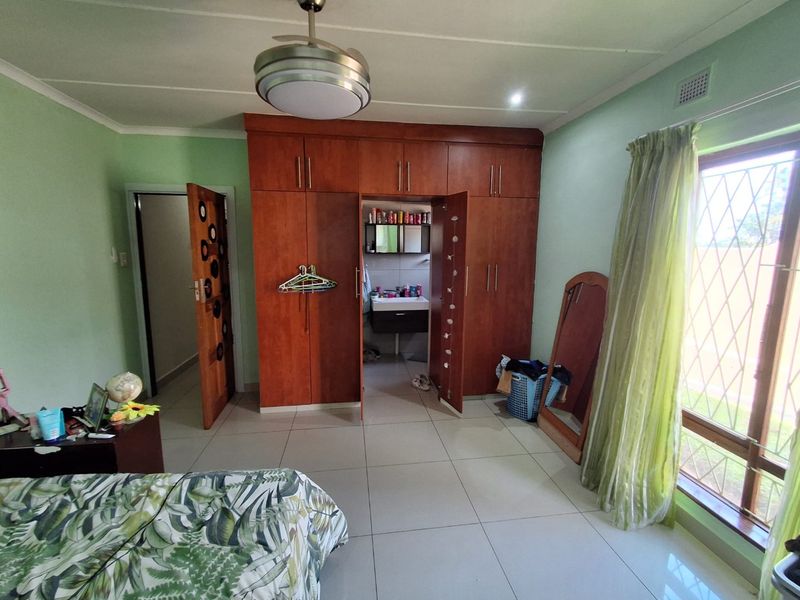 Bedroom featuring built-in wooden cupboards, tiled flooring, a ceiling fan, and an en-suite bathroom access point.