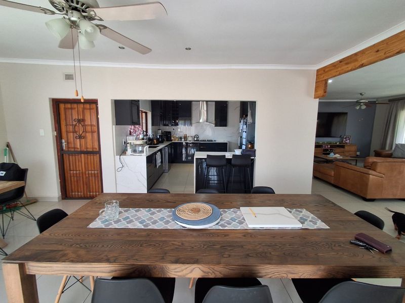 Open-plan living area featuring a modern kitchen with island, tiled flooring, and a ceiling fan, seamlessly connecting to the dining and lounge spaces.