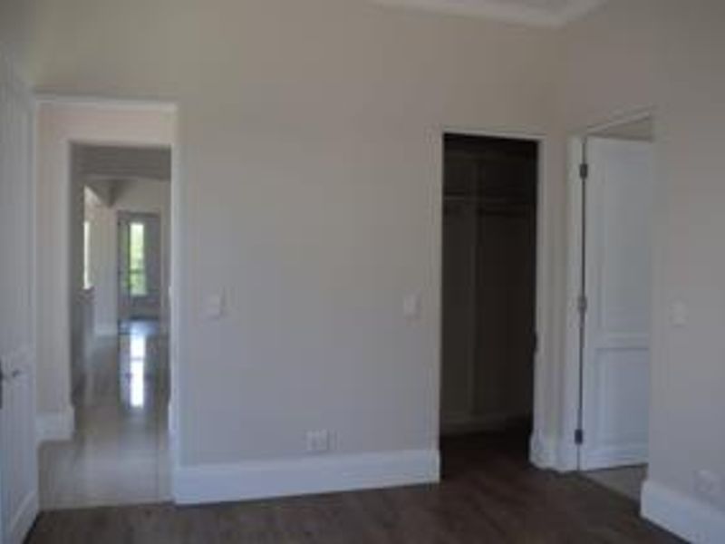 A clean, empty bedroom featuring neutral walls, laminate flooring, and a built-in closet, offering a blank canvas for personalization.
