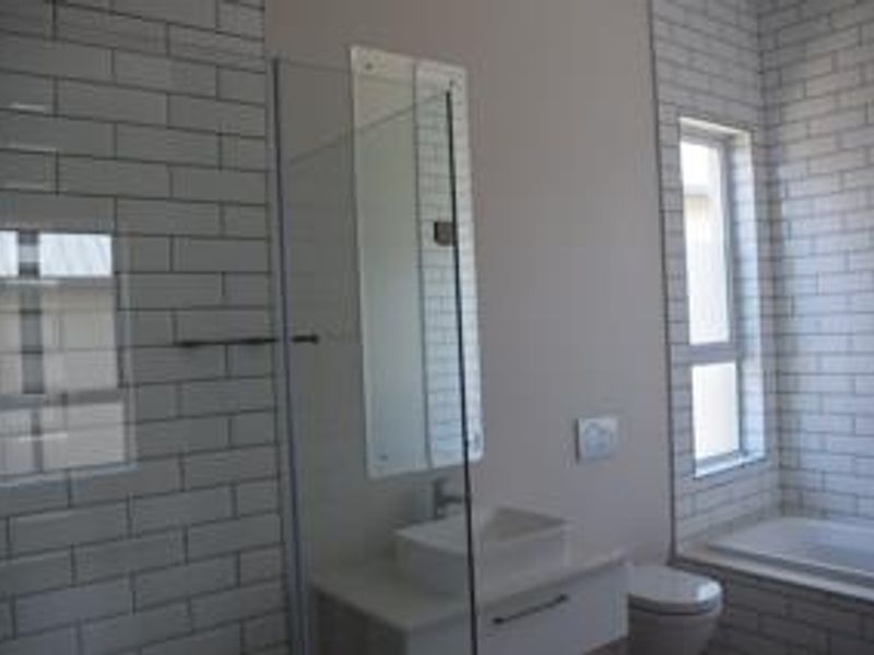 Modern bathroom featuring subway tile wall cladding, a glass shower enclosure, a built-in bathtub, and a vanity with an integrated basin.