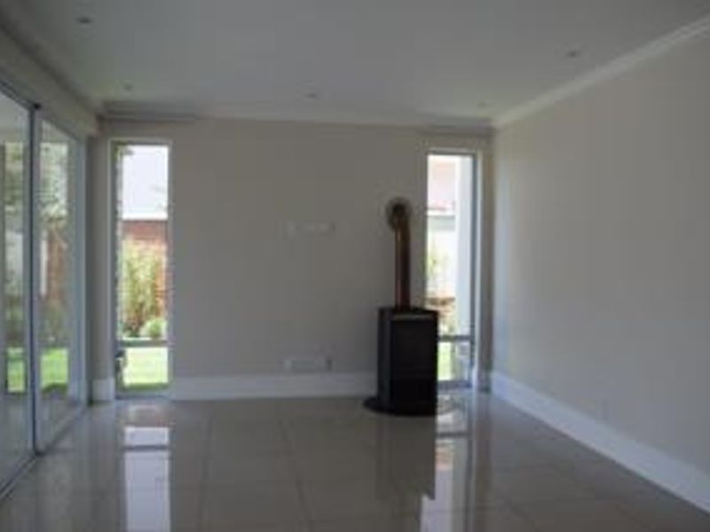 Spacious living area featuring polished tile flooring, a modern freestanding fireplace, and large sliding glass doors providing natural light and garden access.