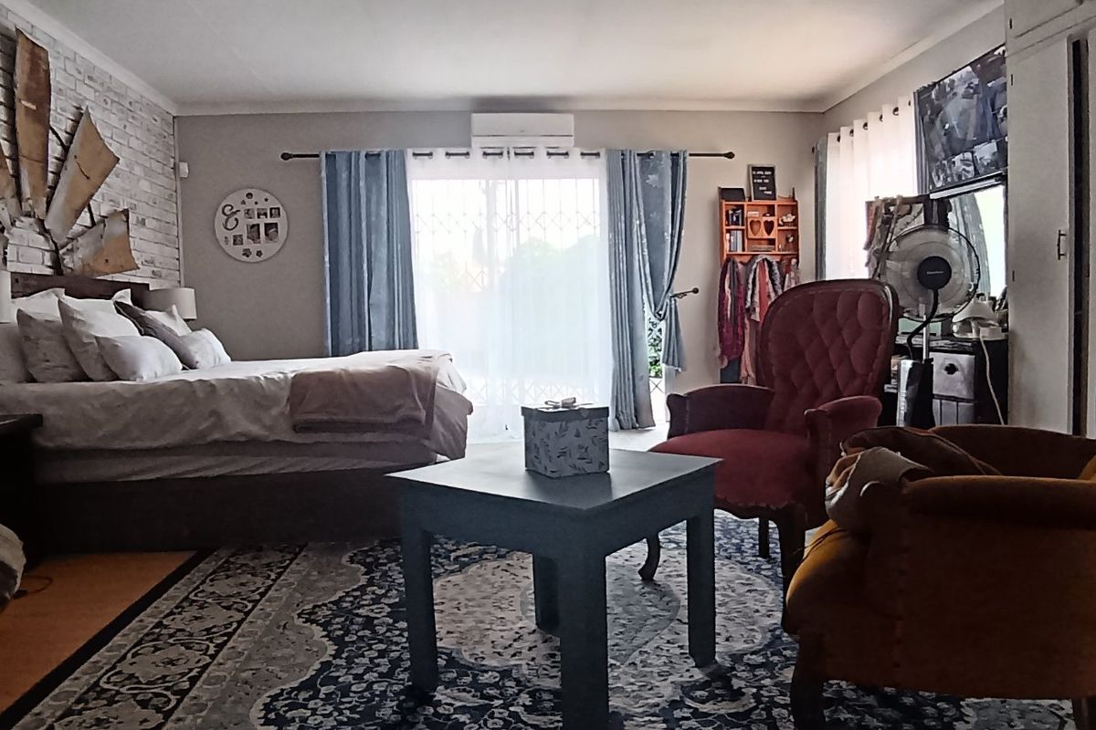 Spacious bedroom featuring an exposed brick accent wall, built-in storage, and direct access to the outdoors via sliding glass doors.