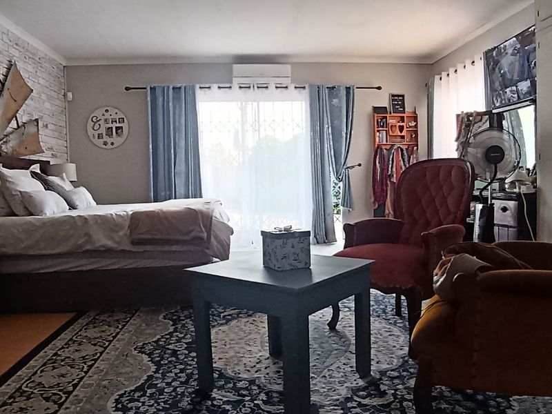 Spacious bedroom featuring an exposed brick accent wall, built-in storage, and direct access to the outdoors via sliding glass doors.
