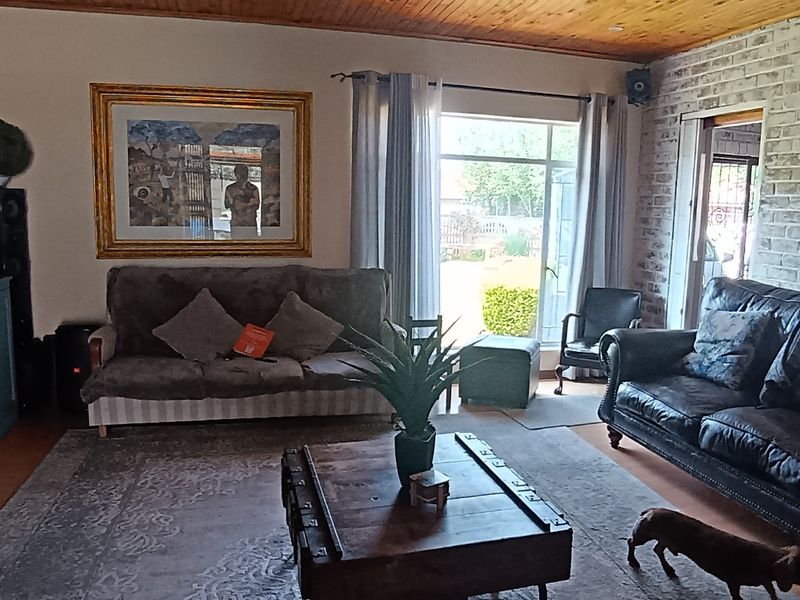A living room featuring an exposed brick feature wall, timber ceiling, and sliding glass door providing access to the outdoor area.