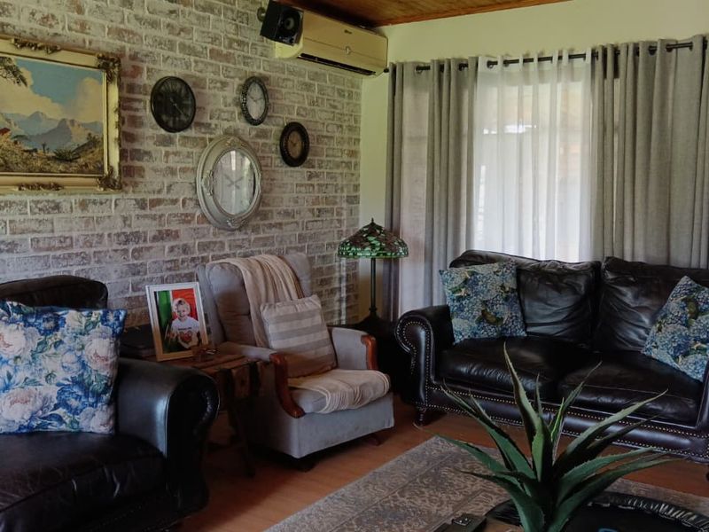 A cozy living room featuring an exposed brick feature wall, timber ceiling, and split-system air conditioning, with direct access to the outdoor area.
