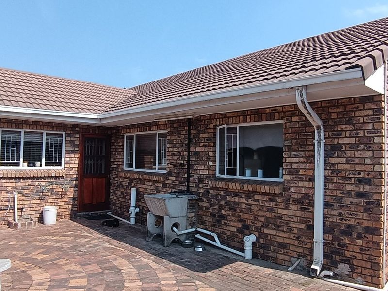 Rear view of a face brick house featuring a paved patio area, external laundry sink, and secure access door.