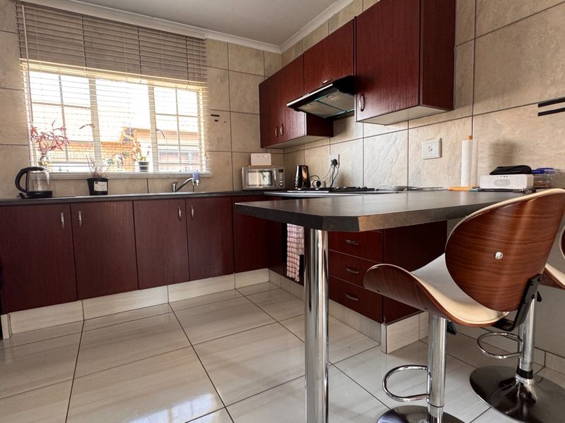 A functional kitchen featuring dark wood cabinetry, laminate countertops, a breakfast nook, and tiled finishes throughout.