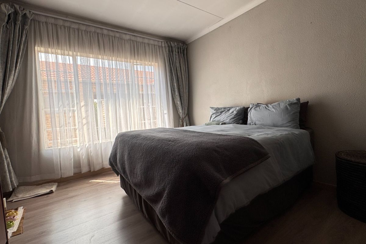 A bedroom featuring laminate flooring and large windows with curtain tracks, offering a neutral space ready for personalization.