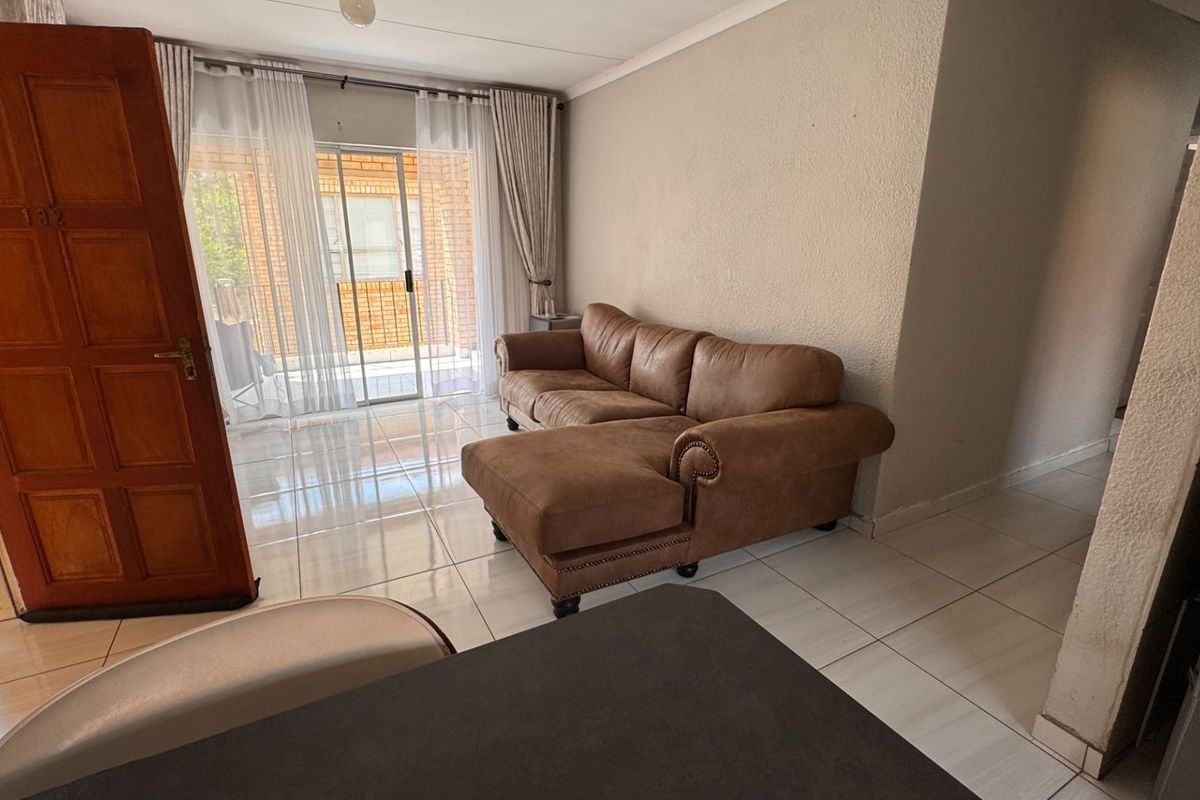A living room area featuring tiled flooring and a sliding glass door providing access to the exterior patio.