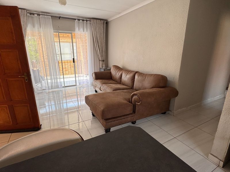 A living room area featuring tiled flooring and a sliding glass door providing access to the exterior patio.