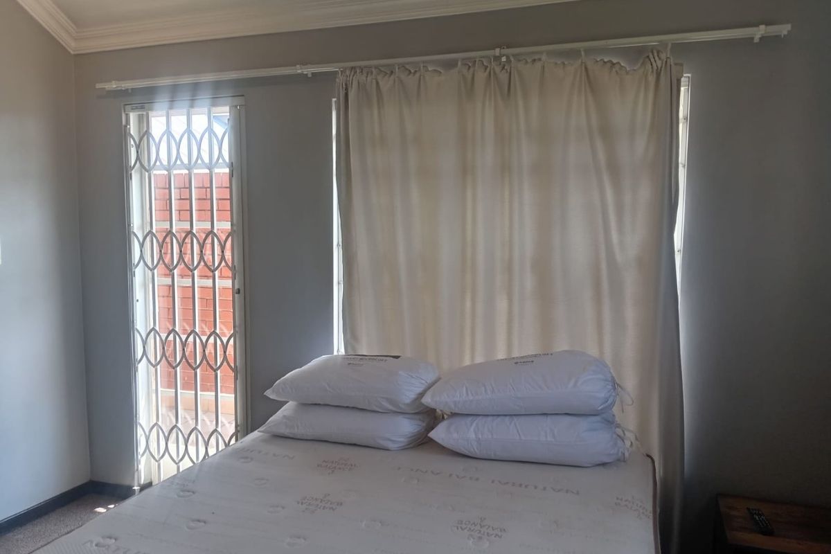 A bedroom featuring neutral walls, crown molding, and a security gate leading to an outdoor area.