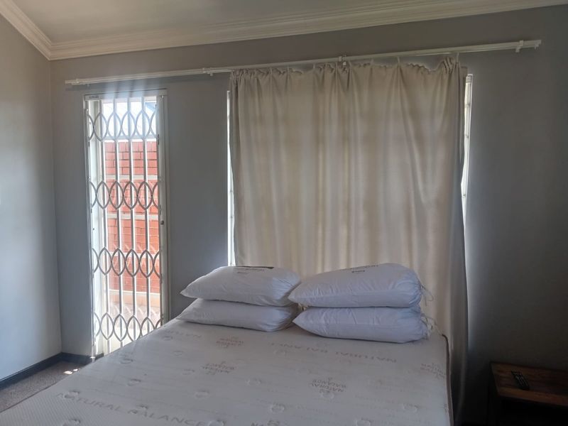 A bedroom featuring neutral walls, crown molding, and a security gate leading to an outdoor area.