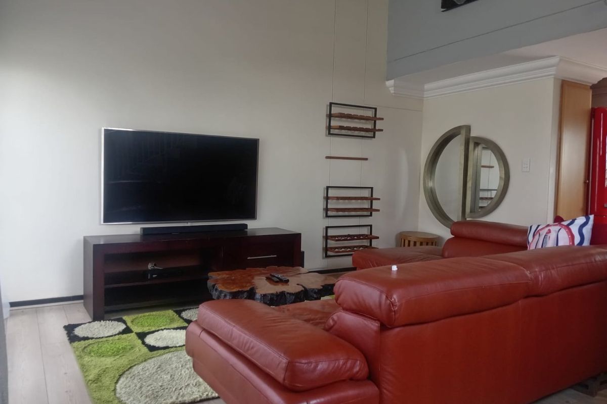 A spacious living room featuring high ceilings, crown molding, and light-toned laminate flooring, offering a comfortable and open atmosphere.