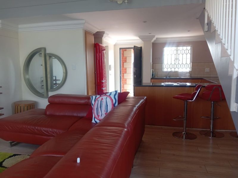 Open plan living area featuring laminate flooring, a kitchen with granite countertops, and direct access to an exterior entrance.