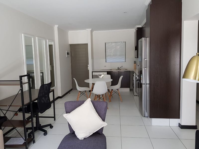 An open-plan living and kitchen area featuring tiled flooring, modern dark cabinetry, and a functional layout suitable for dining and daily living.