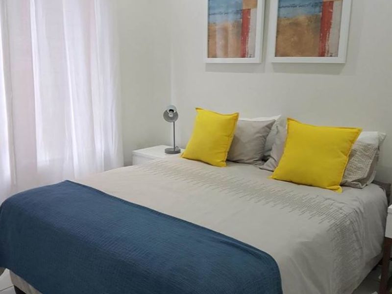 A well-maintained bedroom featuring neutral tiled flooring and a simple curtain rod installation.