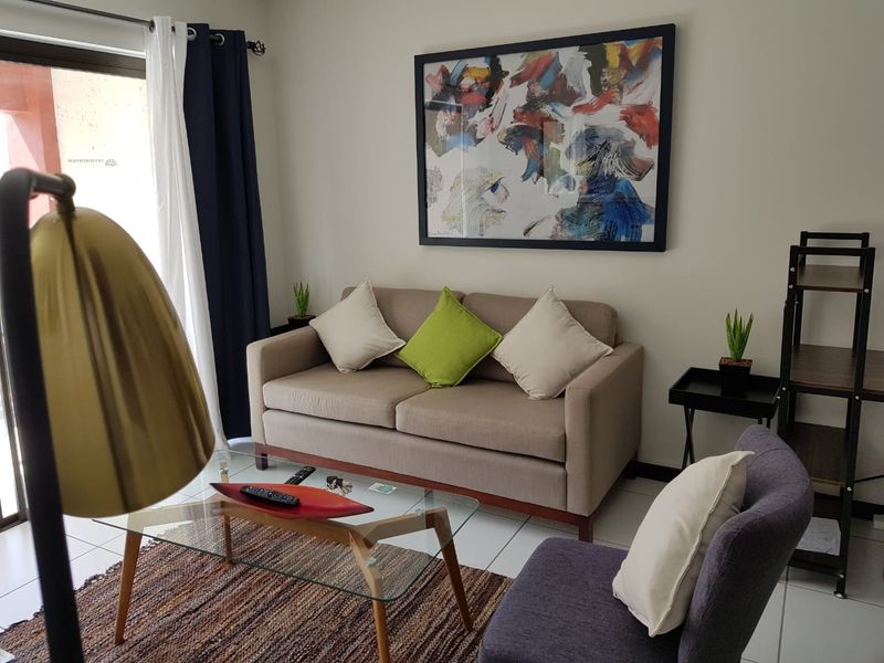 A well-lit living room featuring neutral tiled flooring and a sliding glass door providing access to the outdoor area.