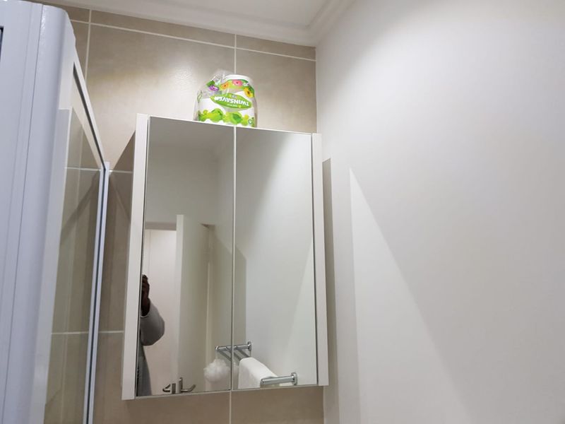 A clean bathroom featuring a wall-mounted mirrored medicine cabinet and neutral wall tiling.