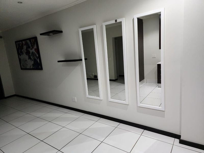 A clean, well-lit hallway featuring white tiled flooring, neutral walls, and modern recessed lighting, providing a bright transition space within the townhouse.