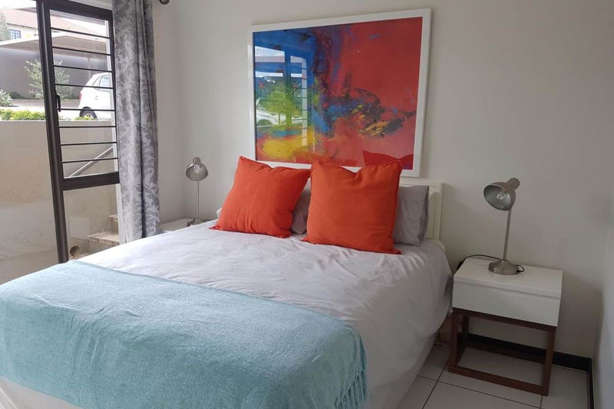 A well-lit bedroom featuring tiled flooring and a sliding glass door providing access to the exterior.