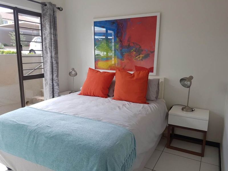 A well-lit bedroom featuring tiled flooring and a sliding glass door providing access to the exterior.