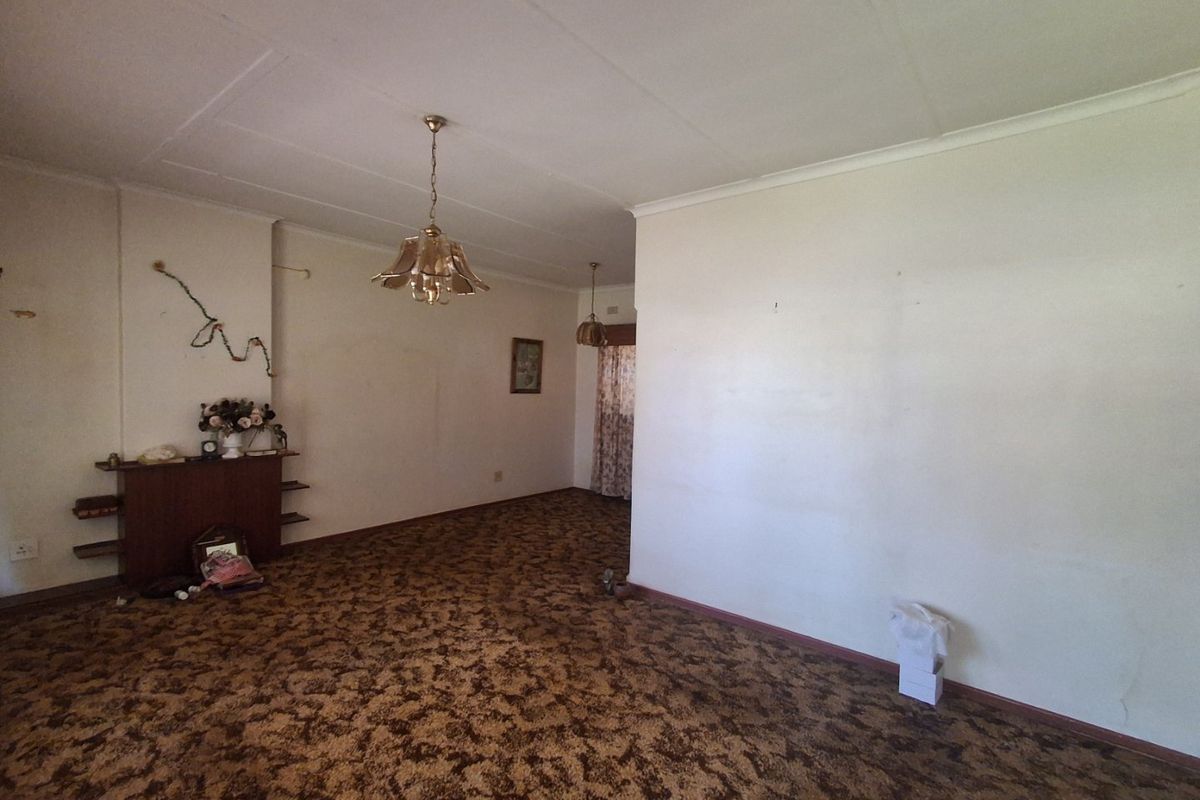 Spacious living area featuring a built-in fireplace mantle and original carpet flooring, offering a blank canvas for renovation and modernization.