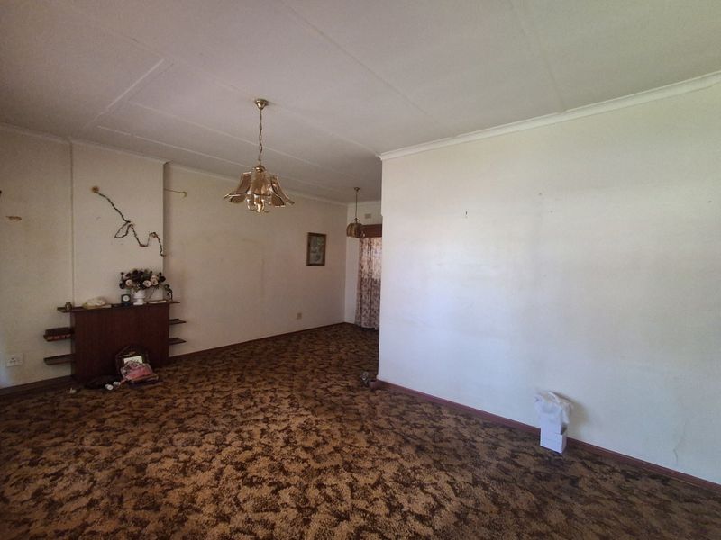 Spacious living area featuring a built-in fireplace mantle and original carpet flooring, offering a blank canvas for renovation and modernization.