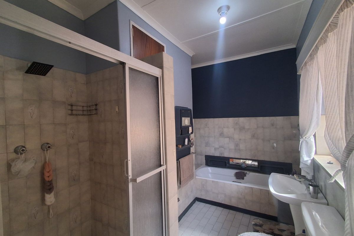 A functional bathroom featuring a separate shower enclosure, built-in bathtub, pedestal basin, and toilet with tiled finishes throughout.