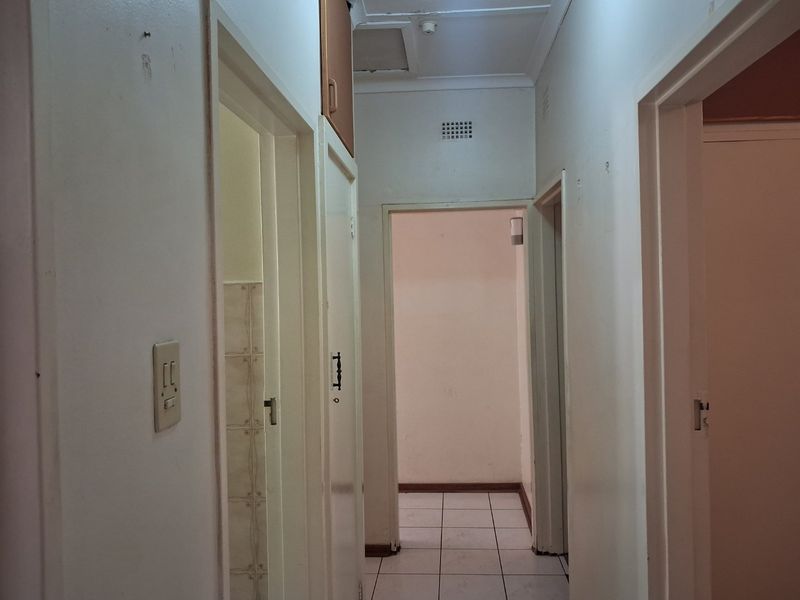 A functional hallway featuring tiled flooring and built-in storage cupboards, providing access to multiple rooms within the home.
